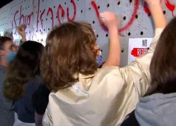 დემონსტრანტები ცესკოს შენობასთან განთავსებულ რკინის ჯებირებს ჯოხებს და ქვებს ურტყამენ